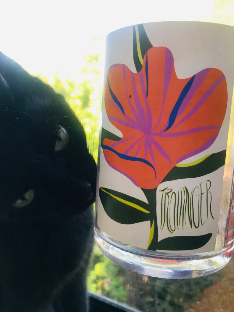 Trollinger wine label with colorful red flower and a black cat sniffing the side